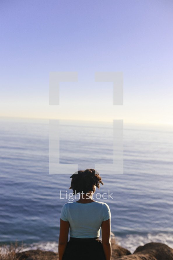 a woman looking out at calm water 