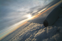 Airplane wing in the clouds flying at sunset