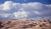 clouds in the sky over desert sand dunes