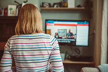 a woman watching an online worship service at home 