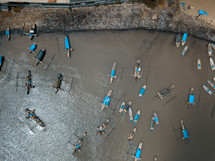 aerial view over boats in a muddy bay 