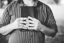 man standing holding a Bible to his chest 