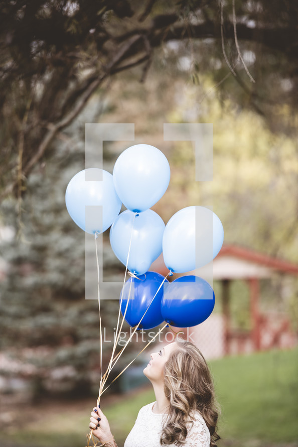 woman holding blue balloons 