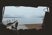 sitting in the back of an SUV looking out at a lake 