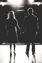 couple standing on stage holding hands 
