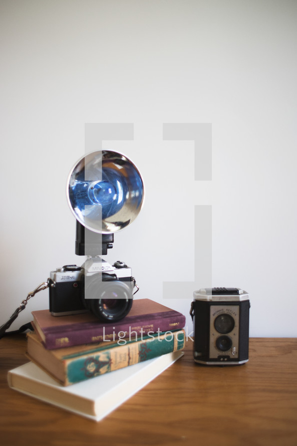 vintage camera with flash on a stack of books 