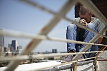 A man praying on a rooftop with hands laced