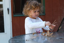 a toddler with pine straw and leaves 