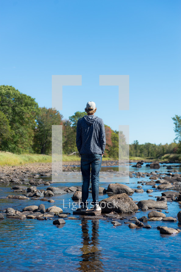 a young man standing on rocks in a river 