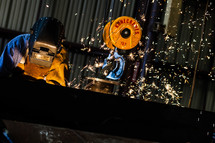 Sparks flying as Man welding welder hood mask industrial steel crane air arcing 