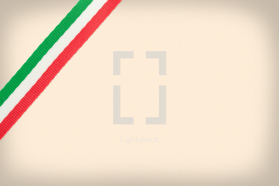 Tricolor ribbon of the Italian flag placed in the corner on beige background