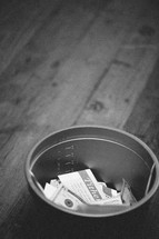 bucket with cash and envelopes for offering