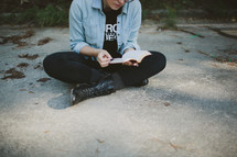 Teen reading Bible outdoors