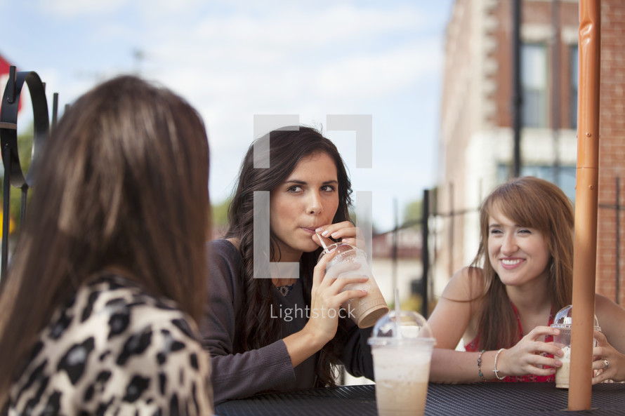 friends sitting at an outdoor table drinking milkshakes 