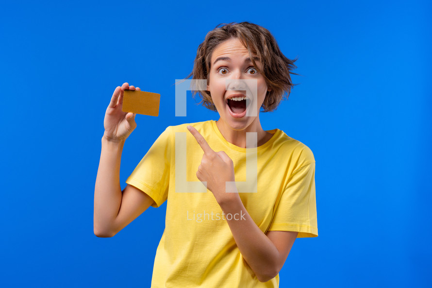 Successful pretty woman showing unlimited gold credit card and look to camera blue studio background. High quality photo
