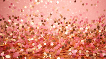 Falling gold confetti on pink background.