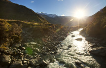 The sun shines bright on a lazy, trickling creek in the mountains at sunrise or sunset.
