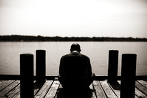 A man sitting on a dock praying