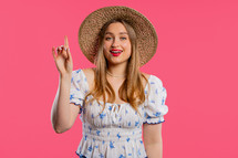 Happy woman having idea eureka moment, pointing finger up on pink background. Clever lady showing answer gesture or remembered what she forgot, memory concept. High quality
