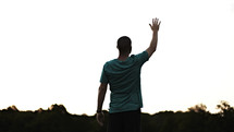 A young adult man lifting his hand in worship