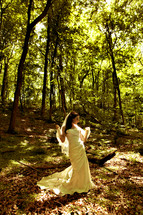 Bride standing in a forest in her gown