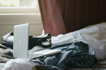 laptop computer, jean jacket, and purse on a bed 