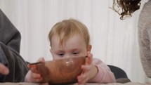 Cute baby eating an orange out of a glass bowl