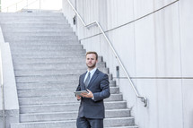 portrait of a businessman holding a tablet in front of stairs 