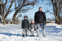 portrait of a father and his sons standing in the snow 