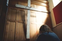 a woman covering her face in shame praying in front of a cross in a church 