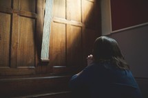 a woman praying in front of a cross in a church 