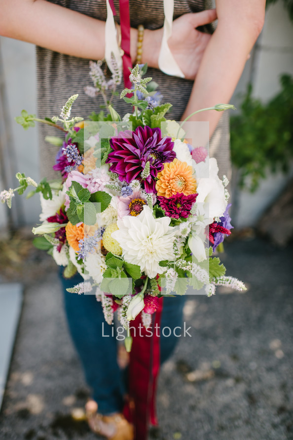 a woman holding a bouquet of flowers behind her back 