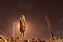 woman standing on rocky soil in front of a street light