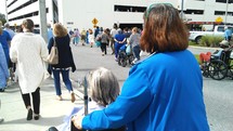 A hospital patient in a wheel chair with her Nurse care giver at a local Hospital with other patients going outside for fresh air and therapy. 