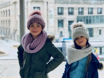 little girls in knit hats and scarfs 