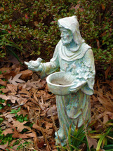 A statue of Patron Saint Francis ministering to birds while surrounded by fallen leaves in the fall of Virginia. 