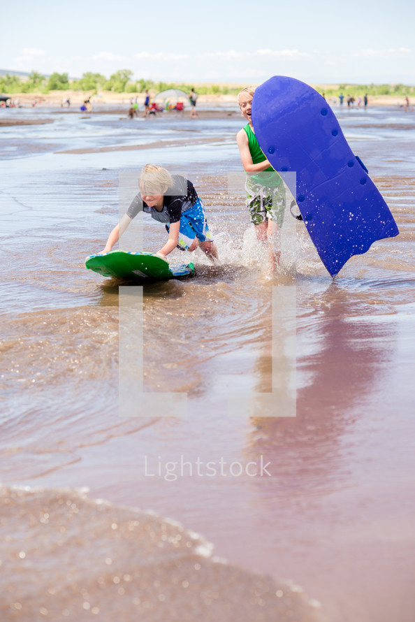 a boy with a skim board on a beach 