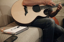 torso of a man sitting and playing a guitar