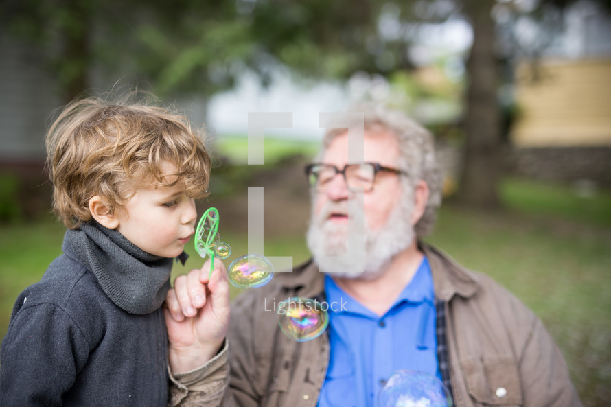 grandfather and grandson blowing bubbles 