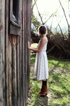 Woman standing beside old wooden home