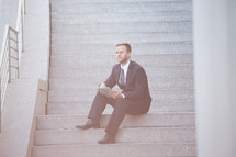 businessman with a tablet sitting on steps 