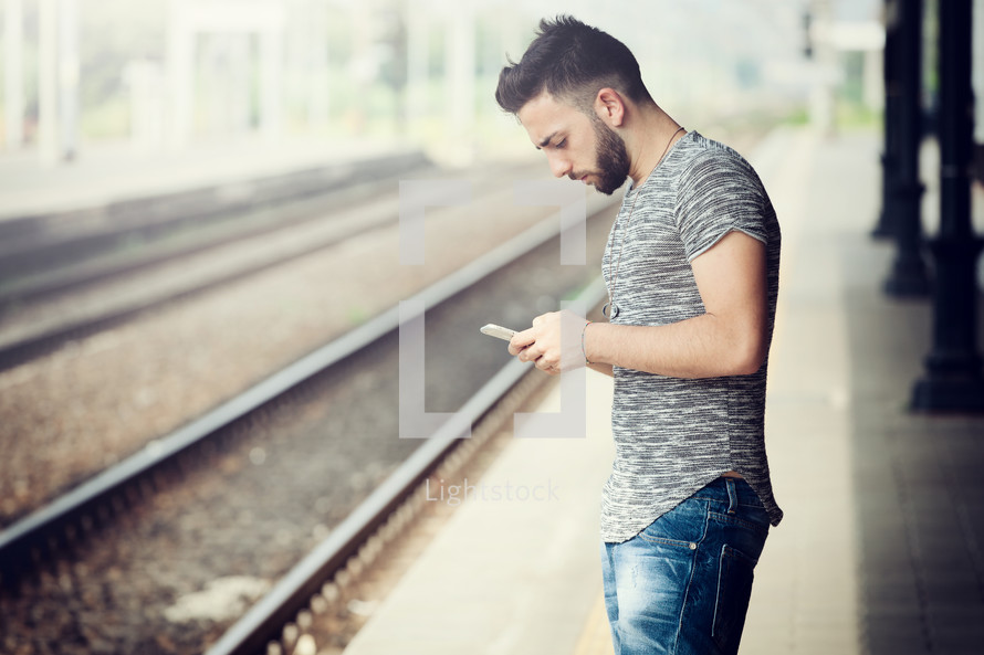 Young Man with smartphone at the train station