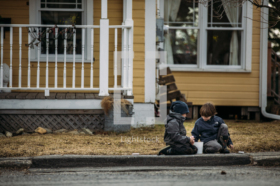 two boys playing outdoors in front of a house 