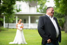 A smiling groom with his eyes closed and back to his bride.
