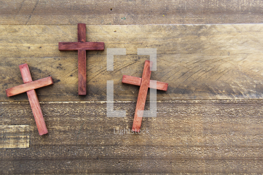 three wooden crosses on a wood background