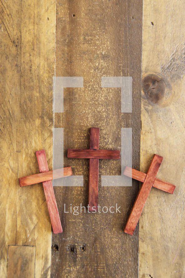 three wooden crosses on a wood background