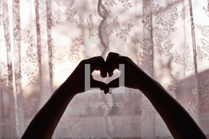 silhouette of hands forming a heart shape 