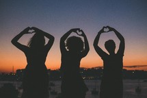 silhouettes of women making hearts with their hands 