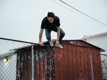 a man climbing over a chain linked fence 