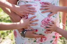 families hands on a mother's belly 